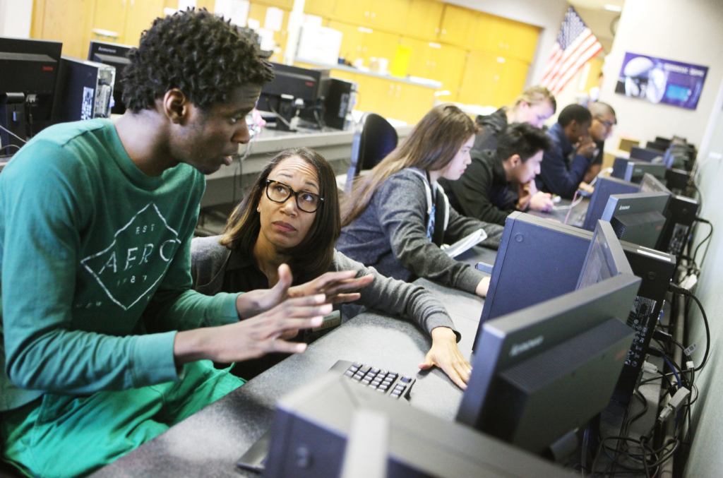 A student and teacher working in front of a computer screen