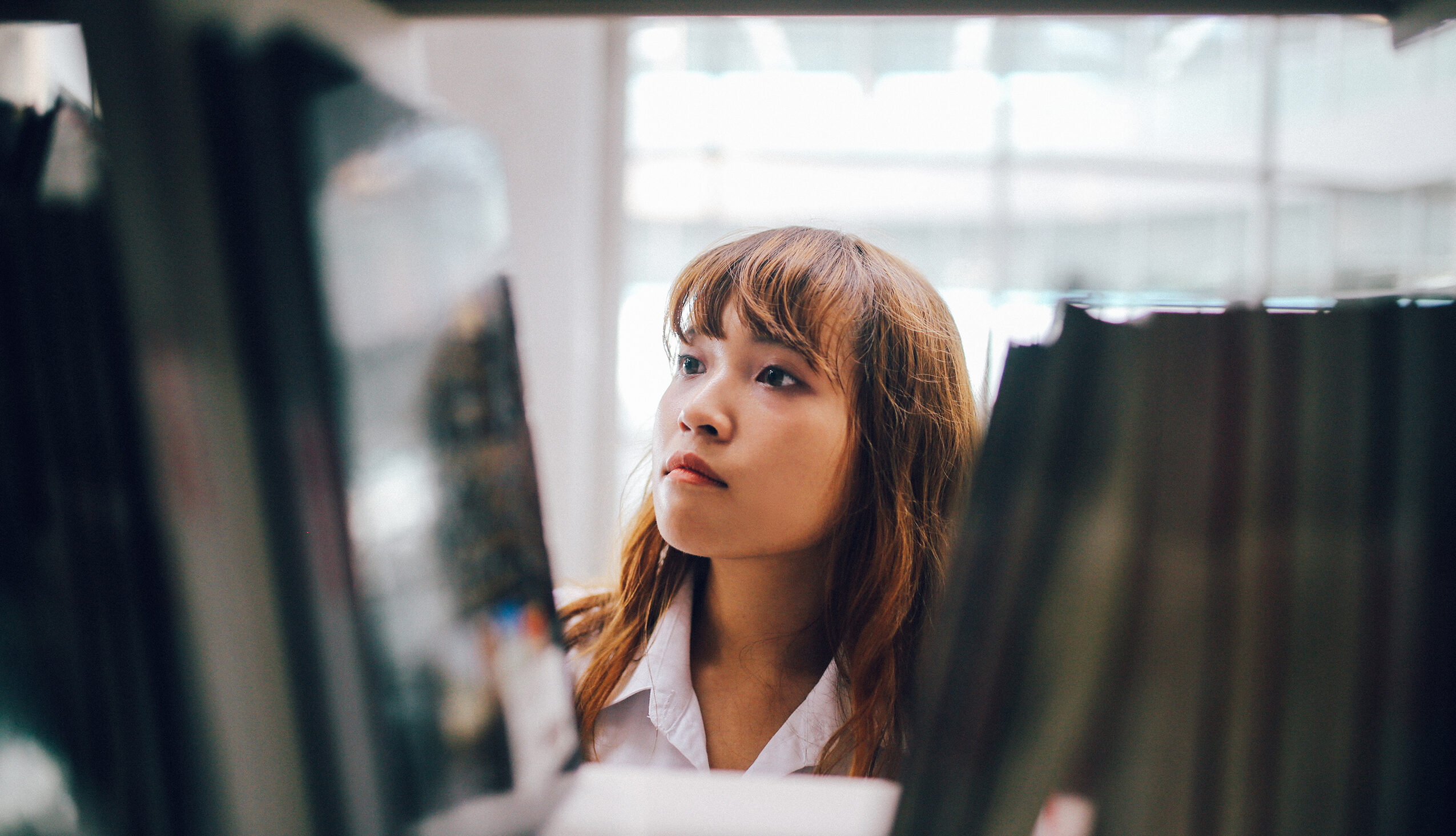 graduate student looking at books on a library shelf