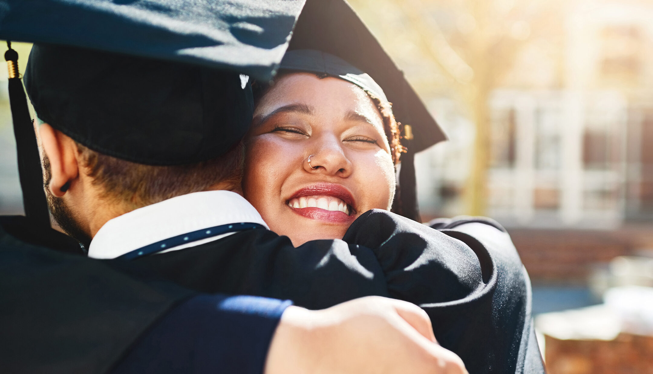 two graduates hugging in their caps and gowns